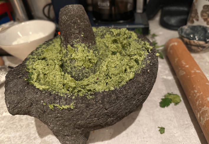 a molcajete with green sauce in it